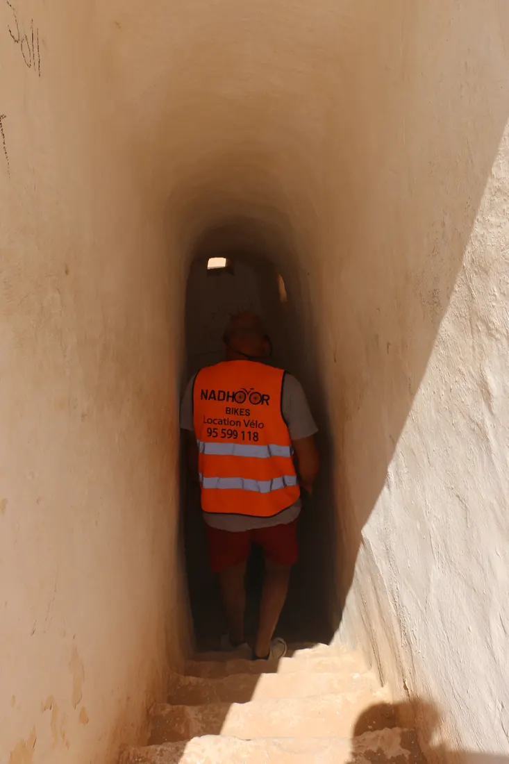Un cycliste descend l'étroit couloir d'une mosquée souterraine