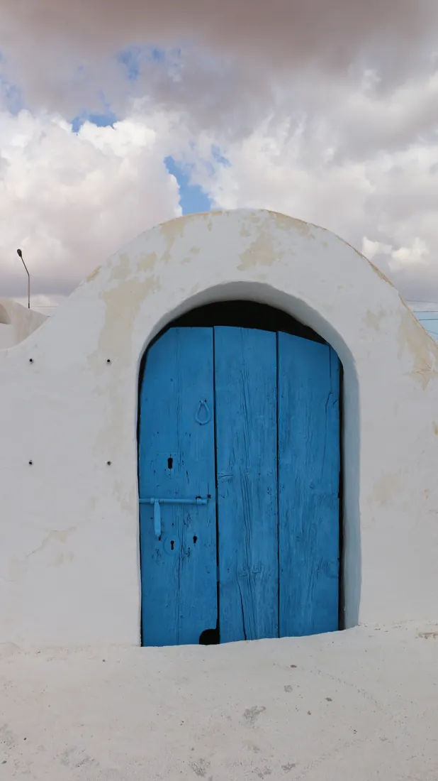 Porte bleue en bois sous une arche blanchie