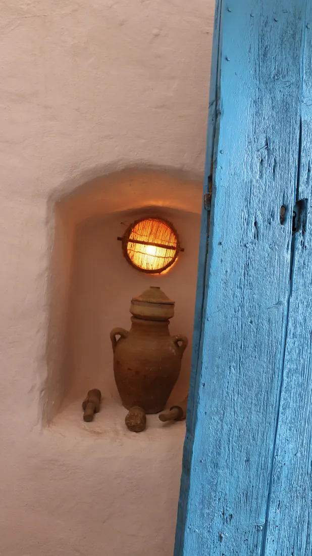Niche éclairée avec une jarre en terre cuite, près d'une porte bleue