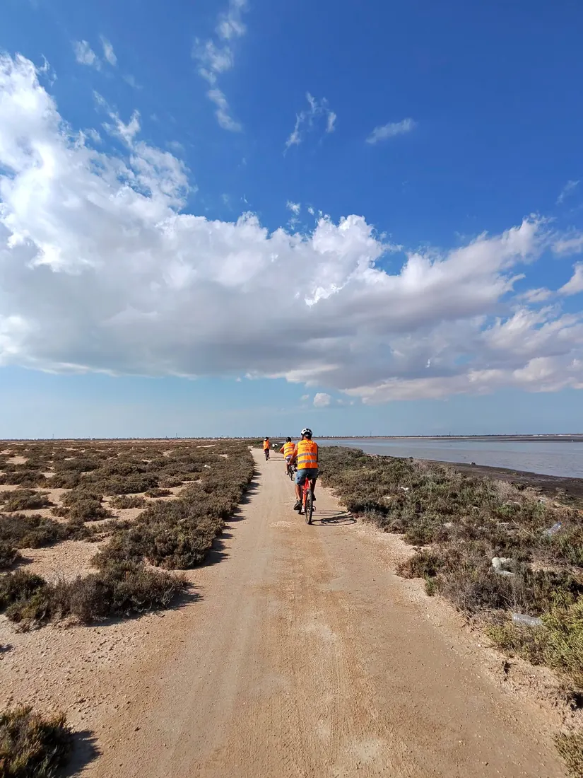 Trois cyclistes sur une piste de sable le long de la lagune