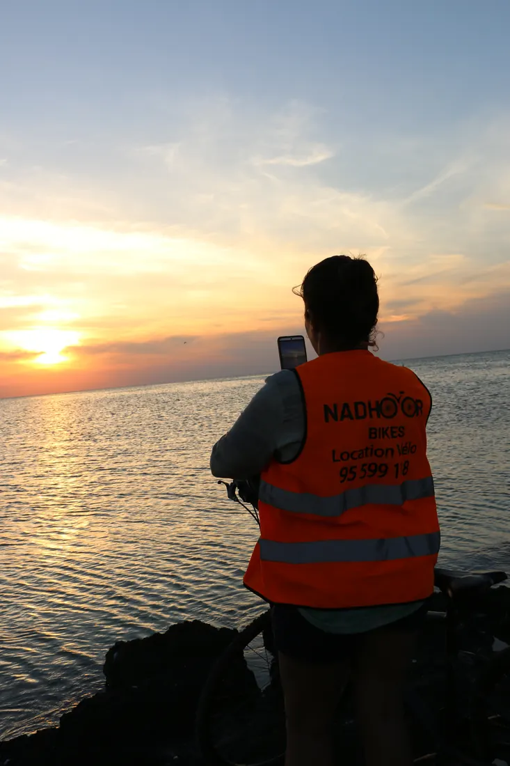 Une participante photographie le coucher du soleil sur la mer