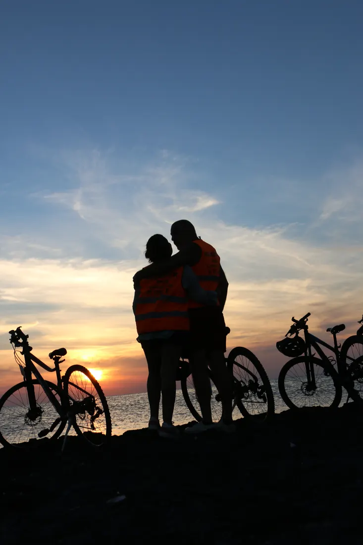 Un couple en silhouette au coucher du soleil, entouré de vélos